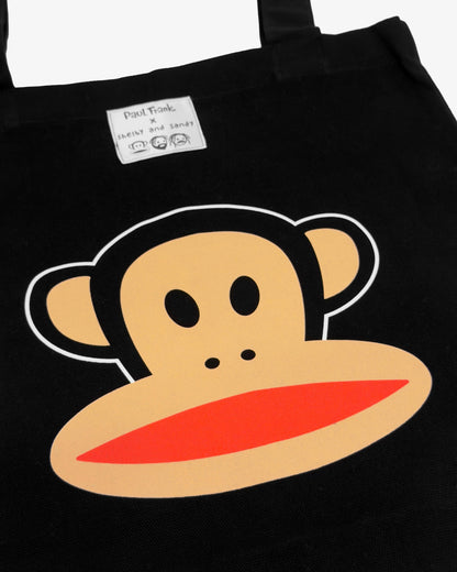 Black tote bag with a cartoon monkey face design on a black background