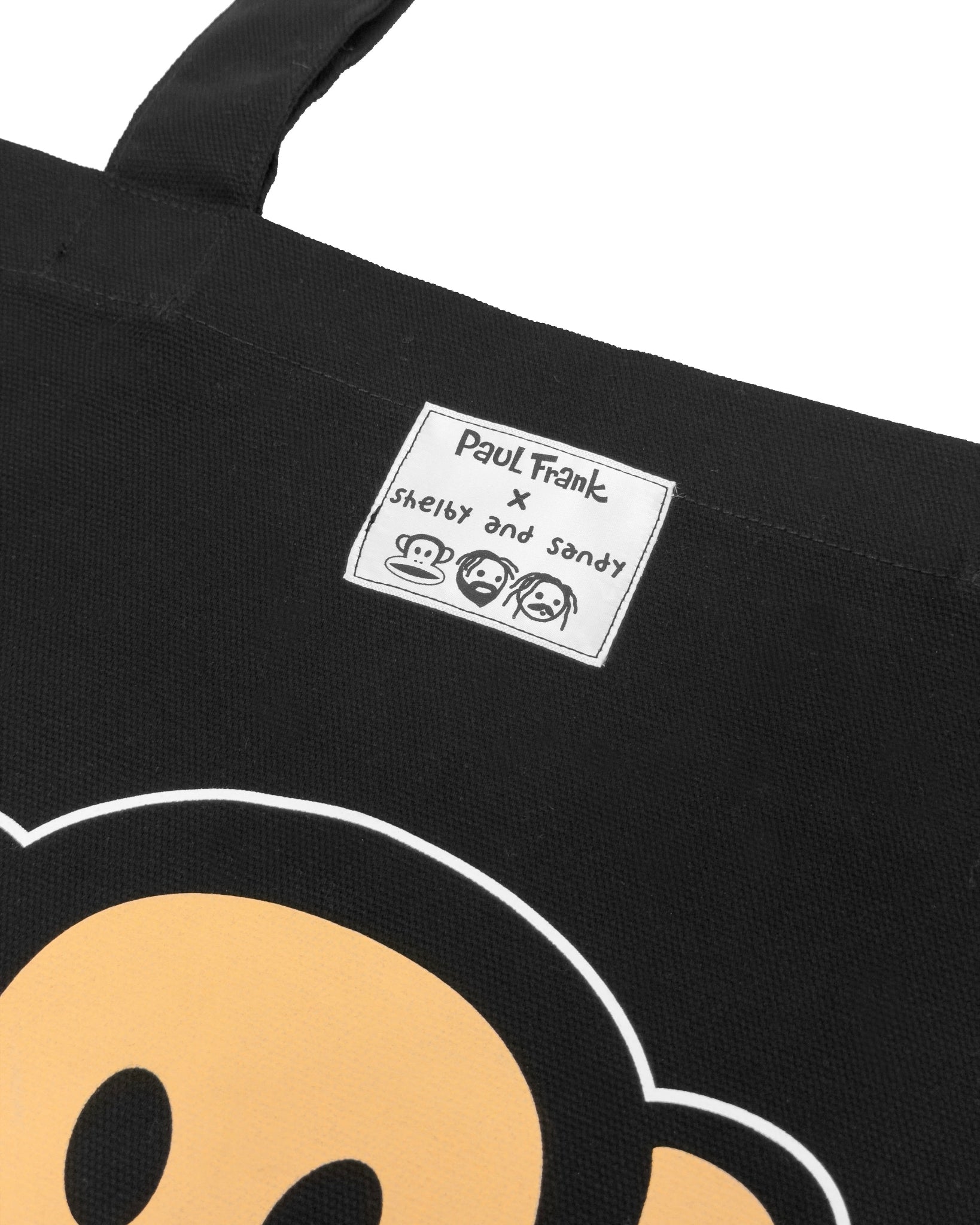 Black tote bag with a monkey character face and Paul Frank x shelby and sandy label